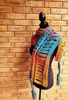 a multicolored shawl on a mannequin next to a brick wall