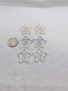 six star shaped charms sitting on top of a white surface next to a quarter penny