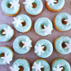 twelve donuts with frosting and sprinkles arranged on a table top