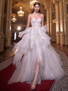 a model walks down the runway in a white gown with large ruffles on it