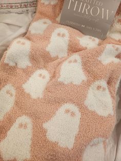 a book is laying on top of a pink and white blanket that has ghostes all over it