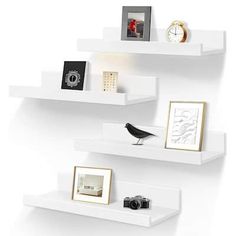 three white shelves with pictures, photos and other items on them against a white wall