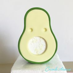 an avocado shaped toy sitting on top of a white block with green trim