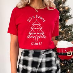 "🎄 \"It's a Beaut, Clark!\" Christmas Tree T-shirt - A Holiday Movie Lover's Dream! 🎄 🎥 Are you a die-hard fan of classic Christmas movies? If you find joy in reliving the magic of holiday films, our Bella and Canvas short sleeve t-shirt is the perfect way to wear your passion with pride! 🎄 A Tree Worth Celebrating: Adorned with a stunning Christmas tree design, this shirt pays homage to one of the most iconic moments in Christmas movie history. The words \"It's a Beaut, Clark!\" are a nod t Festive Crew Neck T-shirt With Letter Print, Festive Letter Print Crew Neck T-shirt, Red Holiday Crew Neck T-shirt, Red Crew Neck T-shirt For Christmas, Holiday Red Crew Neck T-shirt, Festive Holiday Letter Print T-shirt, Red Crew Neck Holiday T-shirt, Red Crew Neck T-shirt For Holidays, Festive Christmas Crew Neck T-shirt