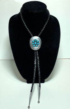 "Vintage Artisan Crafted Sterling Silver Turquoise Bolo Tie Eight gorgeous oval turquoise cabochon gemstones are bezel set on the face of the hand chased silver disk. Tips are also silver. Cord is braided leather. The Disk measures approximately 2.125\" tall and1.75\" wide. Tips are 2.25\" in length. Maker is unknown." Artisan Turquoise Concho Necklace Gift, Adjustable Southwestern Silver Turquoise Necklace, Oval Concho Jewelry Gift, Western Style Engraved Blue Jewelry, Adjustable Oval Artisan Jewelry, Oval Turquoise Inlay Jewelry, Handmade Western Silver Turquoise Necklace, Traditional Turquoise Concho Jewelry, Traditional Turquoise Jewelry With Concho