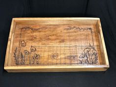 a wooden tray with flowers and plants drawn on the side, sitting on a black background