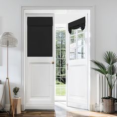 an open door leading to a white room with potted plants