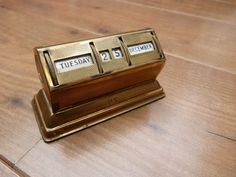 a golden desk clock sitting on top of a wooden table