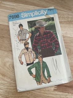 an old sewing book on a wooden table with the cover pulled back to show a man's shirt and pants