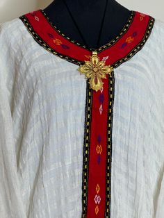 Ethiopian and Eritrean traditional top beautiful dress appears to be a traditional piece with intricate embroidery and a unique design. Could you provide White Embroidered Festive Ceremonial Dress, Festive White Embroidered Ceremonial Dress, White Embroidered Dress For Ceremonial Festive Occasion, Traditional Multicolor Embroidered Tunic Dress, Folk Style Embroidered Dress For Festive Season, Traditional White Embroidered Ceremonial Dress, Traditional White Embroidered Dress For Ceremonies, Traditional Embroidered Dress With Woven Motifs, Bohemian Long Sleeve Habesha Kemis For Festive Occasions