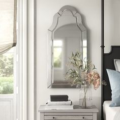 a bedroom with a bed, nightstand and mirror