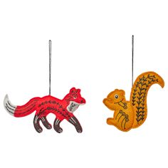 two ornaments are hanging on the wall, one has a squirrel and the other is a fox