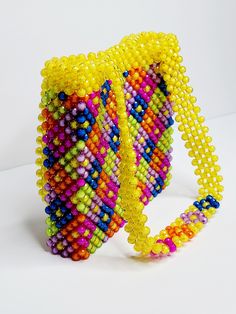 a multicolored beaded bracelet is shown on a white surface with a yellow strap