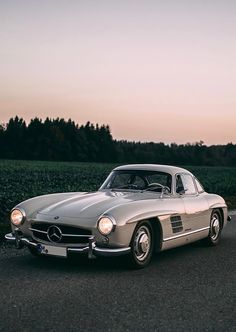 an old mercedes sports car driving down the road