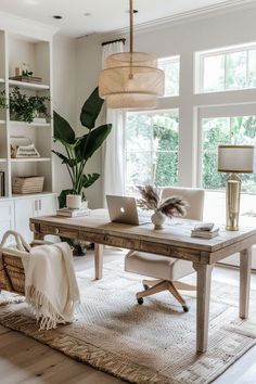 a desk with a laptop on top of it in front of a large window and potted plant