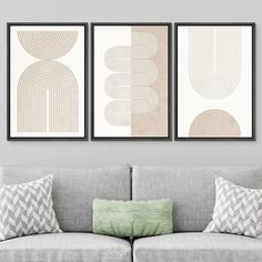 three framed art prints on the wall above a couch in a living room with pillows