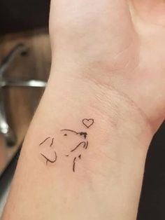 a small wrist tattoo with a dog's head and heart on the left side