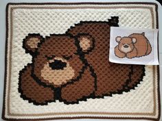 a crocheted bear rug with a brown teddy bear on it's back