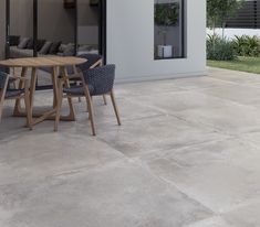 a table and chairs sitting on top of a cement floor next to a patio with sliding glass doors