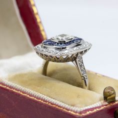 The Taylor ring is a piece handmade in platinum which centers one cushion old mine cut diamond of K color and VS1 clarity that weighs 0.75ctw. The center stone is surrounded by 20 natural calibrated cut sapphires that weigh 1.60ctw and 34 old mine cut diamonds that weigh 0.45ctw. Contemporary Engagement Rings Unique, Sapphire Platinum Diamond Ring Cushion Cut, Sapphire Cushion Cut Diamond Ring In Platinum, Platinum Sapphire Cushion Cut Diamond Ring, Sapphire Diamond Ring With Cushion Brilliant Cut, Sapphire Diamond Ring With Cushion Cut, Sapphire Cushion Cut Diamond Ring, Sapphire Color Cushion Cut Diamond Ring, Sapphire Ring With Brilliant Cushion Cut