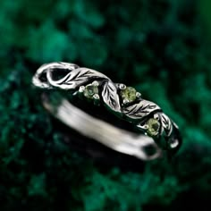 a silver ring with leaves and green stones