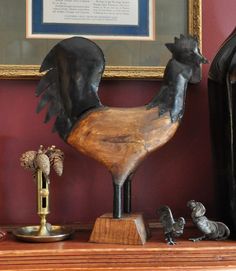 a wooden rooster statue sitting on top of a table next to other figurines