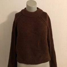 a mannequin wearing a brown sweater and white skirt