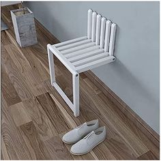 a pair of white shoes sitting on top of a wooden floor next to a chair