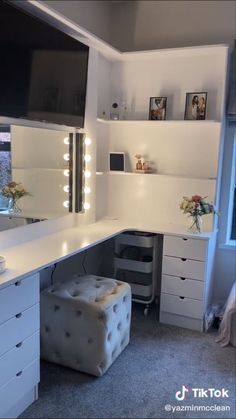 a white vanity with lights on it and a stool in front of the counter top