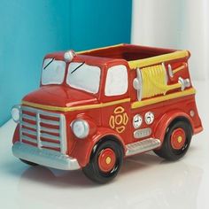 a red toy fire truck sitting on top of a white table next to a blue wall