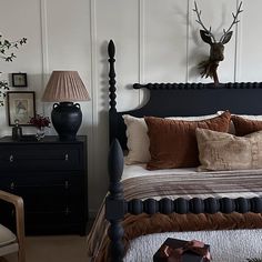 a bed room with a neatly made bed and a deer head mounted on the wall