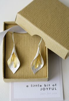 Sterling silver drop earrings with beautiful scrolling cala lily design available in silver only or silver with gold inset. An elegant gift. Marked 925.  Dimensions: 4cm drop. Flower itself is 3 x 1cm.  Shipping and packaging: Your earrings will be beautifully boxed in recycled packaging. Sent within 1-3 working days.  If you're in the UK your Joyful delivery will be sent by Royal Mail 1st class. Etsy will let you know when it's on its way. Overseas deliveries are sent by Royal Mail internationa Sterling Silver Flower Earrings, Lily Design, Faux Pearl Bracelet, Flower Drop Earrings, Sterling Silver Drop Earrings, Botanical Jewelry, Sterling Silver Flowers, Jewelry Manufacturers, Flower Earrings Studs