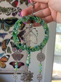 a person holding a green beaded bracelet with charms