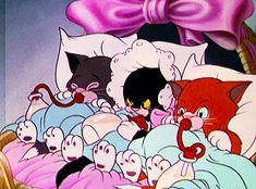 an animated image of cats in bed with pink bows on their head and one cat laying down