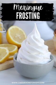 lemon meringue frosting in a bowl next to sliced lemons