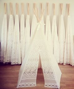 there are many white dresses hanging on the wall with wooden sticks in front of them