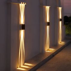 an outdoor wall light with multiple lights on the sides and in between them, against a white stucco wall