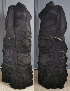 A superb, gothic Victorian antique bustle dress for mourning, dating to the early 1880s / natural form era - excellent condition, and a rare larger size. One piece, in a glossy two tone silk, black, the reverse in purple, the dress reflecting subtle purple tones. Closely fitted to the body, the bodice boned, fastening in the front with woven dome buttons in purple from neck to hip. Small collar, and a small waist patch pocket. Long fitted sleeves, with gathered cuffs and lace trim on the inner e Victorian Dress With Ruffles For Theater, Victorian Ruffled Dress For Theater, Black Victorian Dress Costume, Black Victorian Dress For Costume, Ruffled Victorian Dress For Theater, Fitted Historical Victorian Dress For Larp, Black Historical Victorian Costume Dress, Historical Black Victorian Costume Dress, Black Victorian Dress With Ruffles