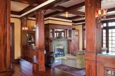 a living room with wood floors and wooden columns on the wall, along with a fireplace