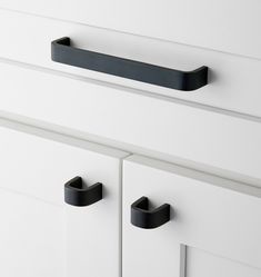 black handles on white drawers in a room