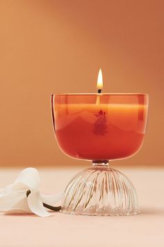 a candle that is sitting on top of a glass bowl next to a white flower