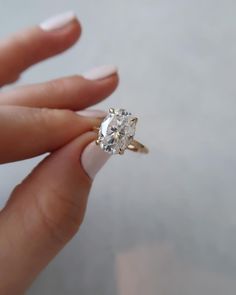 a woman's hand holding an engagement ring with a diamond on the middle finger