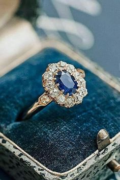 an engagement ring with a blue stone surrounded by white and yellow diamonds in a velvet box