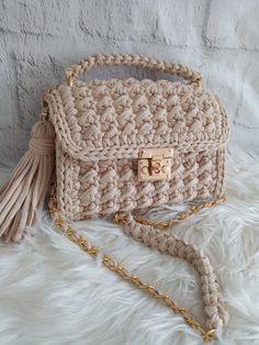 a crocheted purse with a tasselled handle on a white furnishing