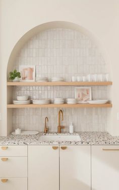 a kitchen with white cabinets and marble counter tops, along with open shelving above the sink