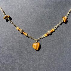 This handmade necklace features a delicate gold chain adorned with a striking heart-shaped, tiger's eye gemstone pendant with bead and gemstone accents along the chain. The warm, earthy tones of the tiger's eye stones add a natural elegance to this unique piece. Perfect for those who love boho and nature-inspired jewelry, this necklace complements any outfit with its rich colors and sophisticated design. The high-quality materials and craftsmanship make it a wonderful gift for birthdays, anniversaries, or any special occasion. Wear it alone for a subtle statement or layer it with other necklaces for a more bohemian look. This is a new shop so please don't be discouraged by the low amount of orders and reviews at this time. Feel free to reach out with any questions, comments, or concerns! Spiritual Heart Bead Pendant Jewelry, Spiritual Heart Beads Pendant Jewelry, Spiritual Pendant Jewelry With Heart Beads, Heart-shaped Beaded Necklaces With Natural Stones, Heart-shaped Beaded Necklaces With Natural Stones For Gift, Heart-shaped Adjustable Necklace With Natural Stones, Spiritual Heart Beads Pendant Necklace, Heart-shaped Beaded Necklace With Natural Stones For Gift, Heart-shaped Natural Stone Beaded Necklace For Gift