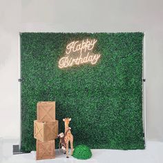 two giraffes standing in front of a green wall with a happy birthday sign