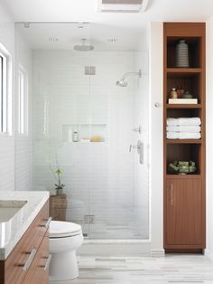 a bathroom with white tile and wooden cabinets