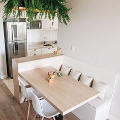 a kitchen table with chairs and a plant hanging from it's ceiling in front of a refrigerator