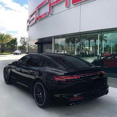 a black porsche parked in front of a porsche dealership